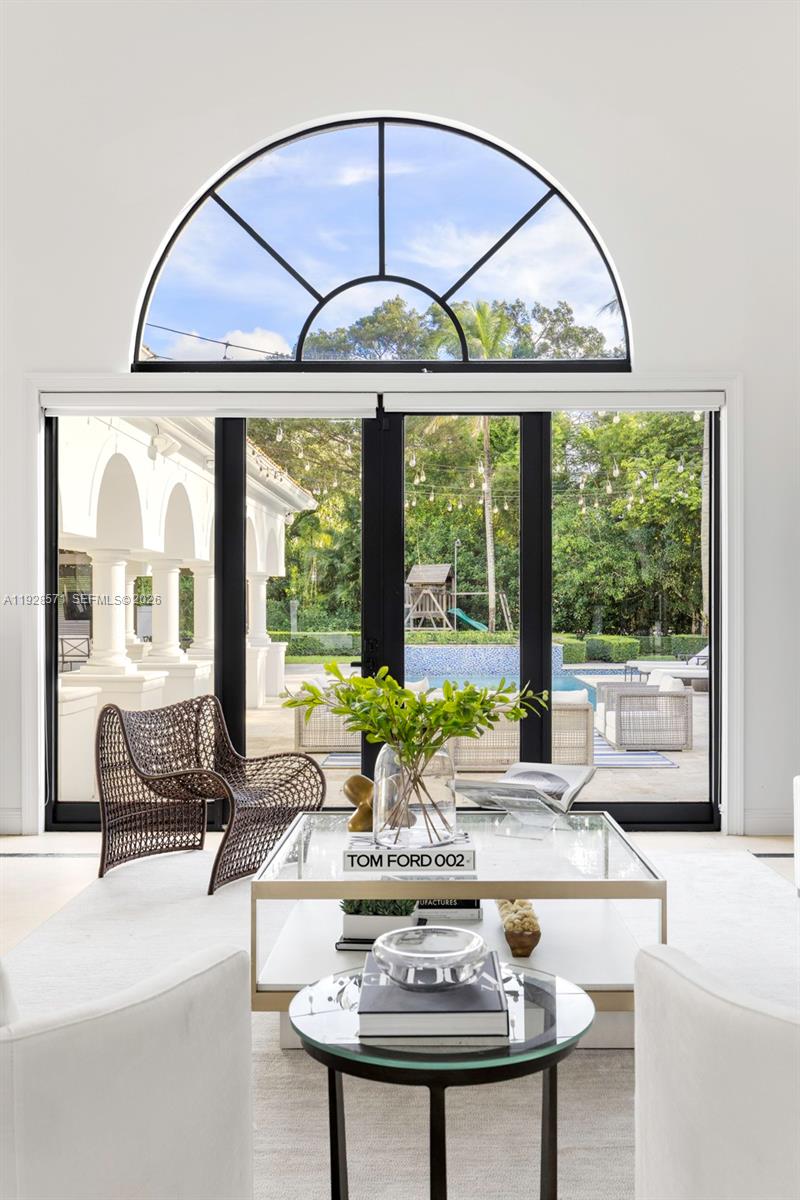 A living room features a large arched window, glass coffee table, and patio view — 7430 SW 66th St, Miami FL 33143, MIAMI, FL