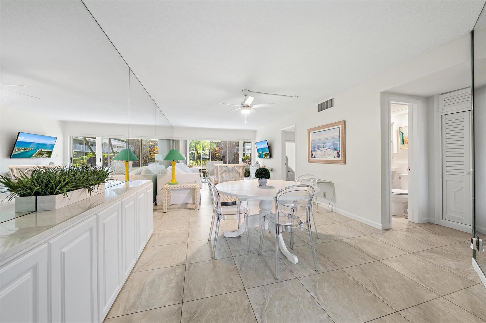 A dining area with a round white table, clear chairs, and a mirrored wall — 50 Celestial Way # 105, Juno Beach FL 33408, JUNO BEACH, FL