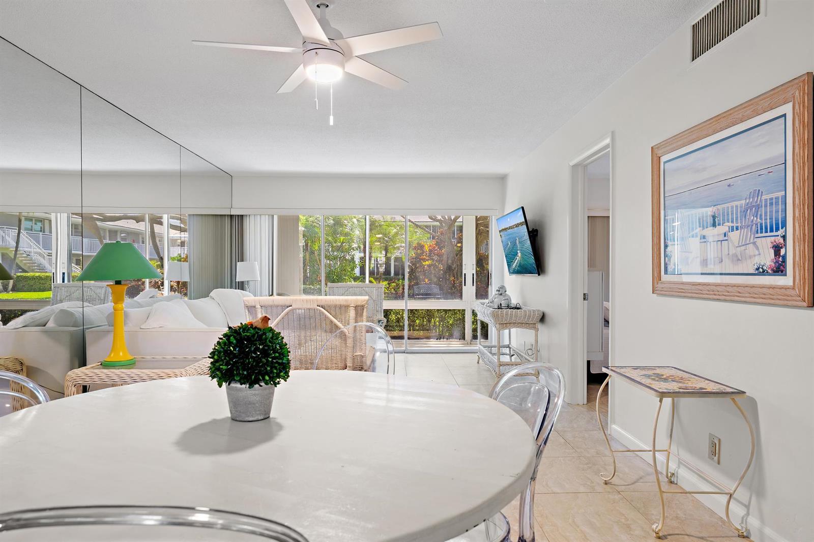 A dining area with a round table and clear chairs opens to a living room — 50 Celestial Way # 105, Juno Beach FL 33408, JUNO BEACH, FL