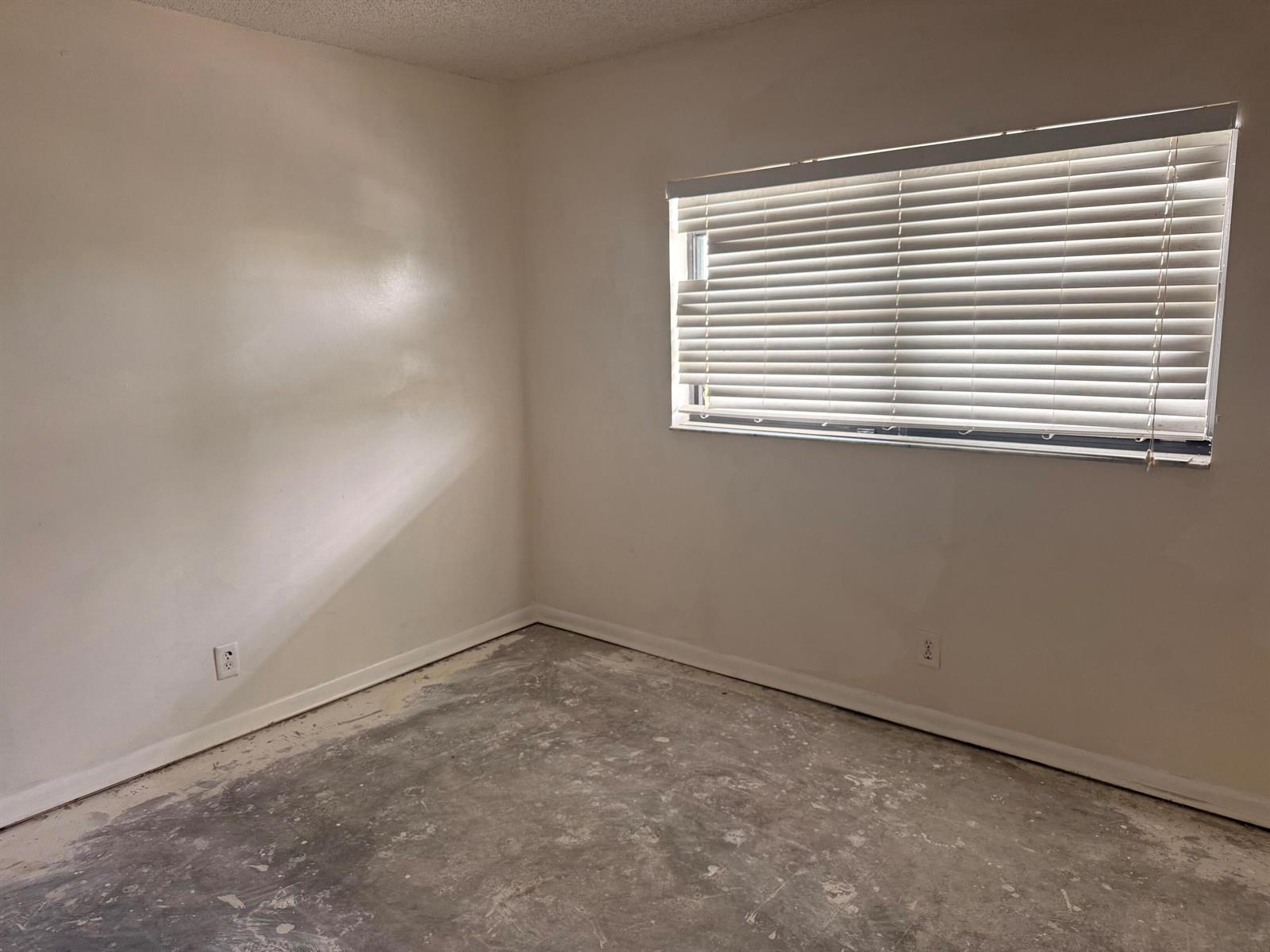An empty room with white walls, a window with blinds, and an unfinished concrete floor — 2021 W Woolbright Road # G205, Boynton Beach FL 33426, BOYNTON BEACH, FL