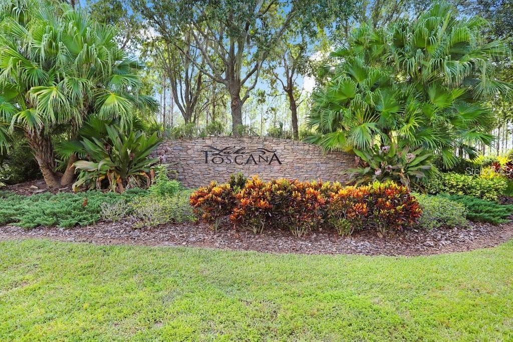 A stone monument sign for Toscana sits in a landscaped garden with palm trees — 5247 LAKE VENICE DRIVE, WIMAUMA, FL