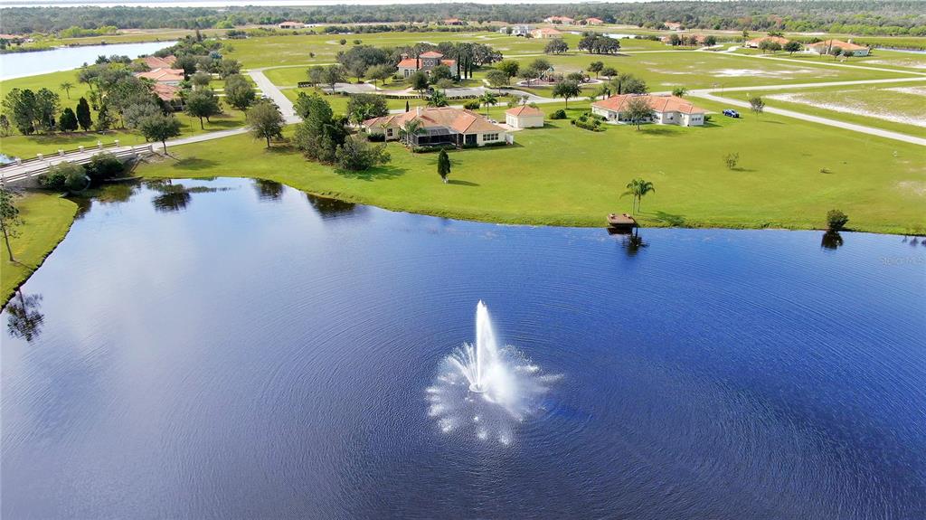 An aerial view of a lake with a fountain in front of several suburban houses — 5247 LAKE VENICE DRIVE, WIMAUMA, FL