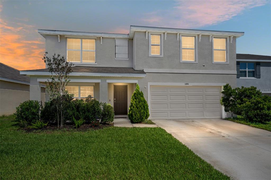 A two-story suburban house with a stucco exterior, a two-car garage, and a front lawn — 5394 SW 40TH CIRCLE, OCALA, FL