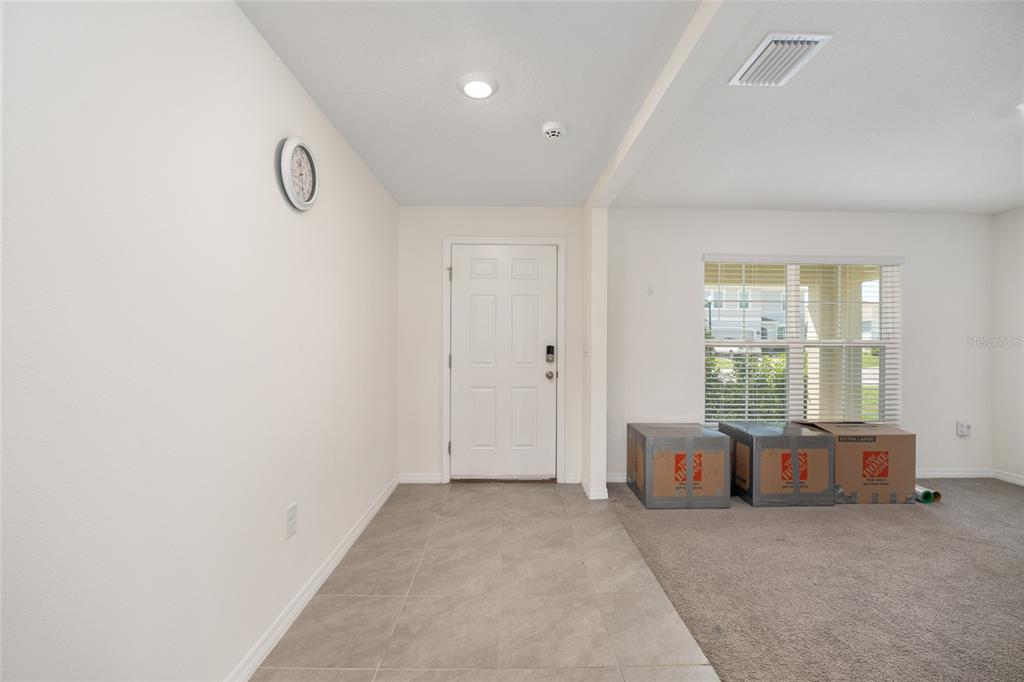 An entryway with tile flooring, a white front door, and carpeted living area with boxes — 5394 SW 40TH CIRCLE, OCALA, FL