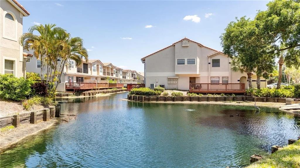 A canal flows between multi-story residential buildings with wooden decks and landscaped grounds — 10438 SAINT TROPEZ PLACE, TAMPA, FL