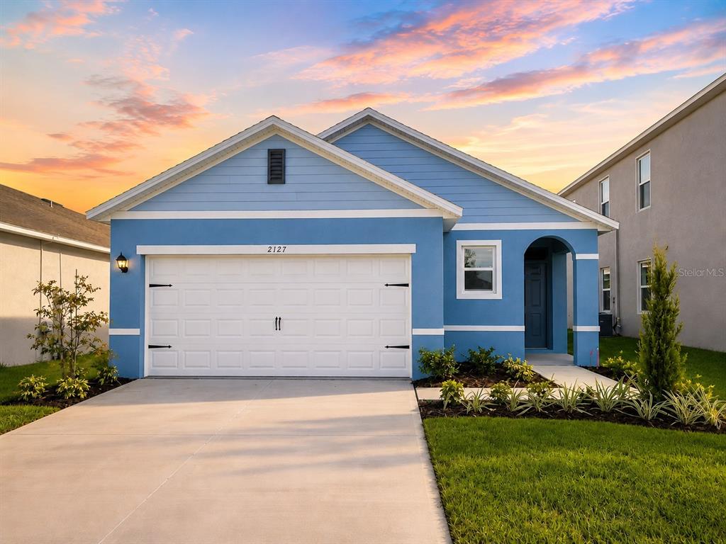 A blue single-story house with a white garage door and a concrete driveway — 2127 DESERT ROSE DRIVE, DAVENPORT, FL