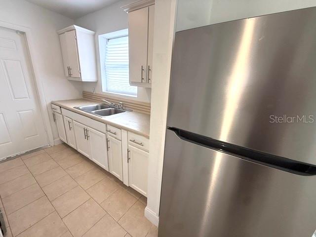 A galley kitchen features white cabinets, beige countertops, stainless steel appliances, and a tile floor — 8766 PORTO BELLO AVENUE, NORTH PORT, FL