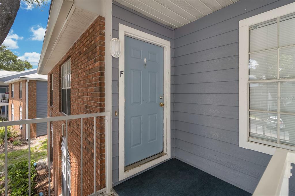 A light blue front door with the letter F is set within a gray-sided exterior — 5417 LAKE MARGARET DRIVE UNIT F, ORLANDO, FL