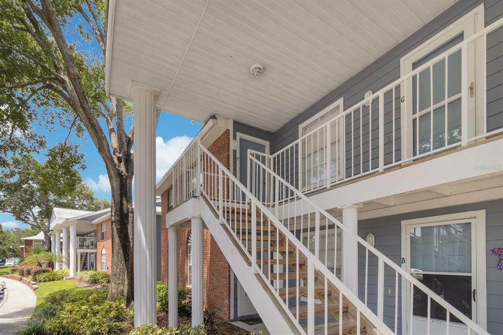 An exterior view of a two-story apartment building with stairs leading to an upper balcony — 5417 LAKE MARGARET DRIVE UNIT F, ORLANDO, FL