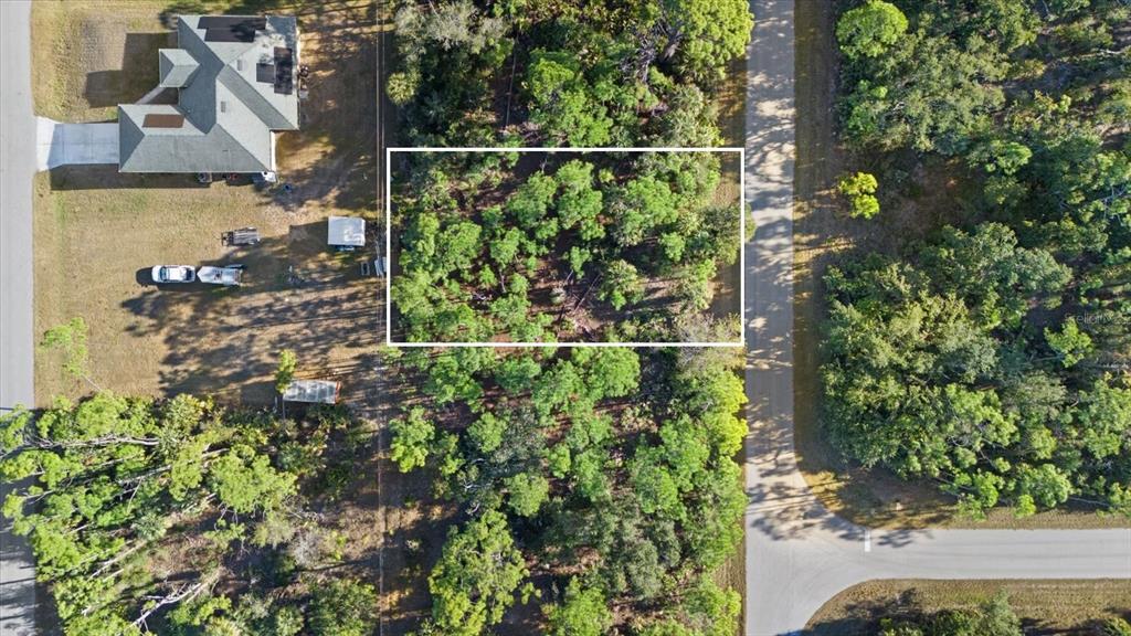 An aerial view shows a rectangular, tree-covered vacant lot outlined in white next to a house — 15074 CANNELL LANE, PORT CHARLOTTE, FL