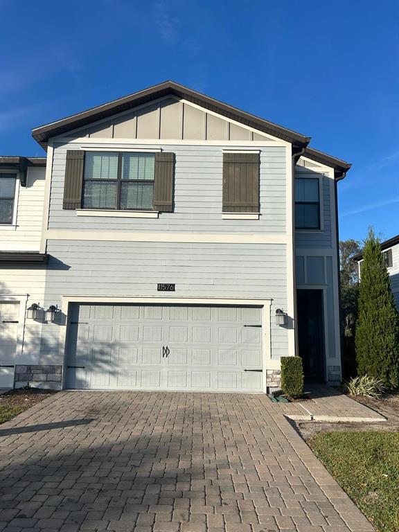A two-story townhouse exterior features light blue siding, a two-car garage, and a paved driveway — 11576 WHISTLING PINE WAY, ORLANDO, FL