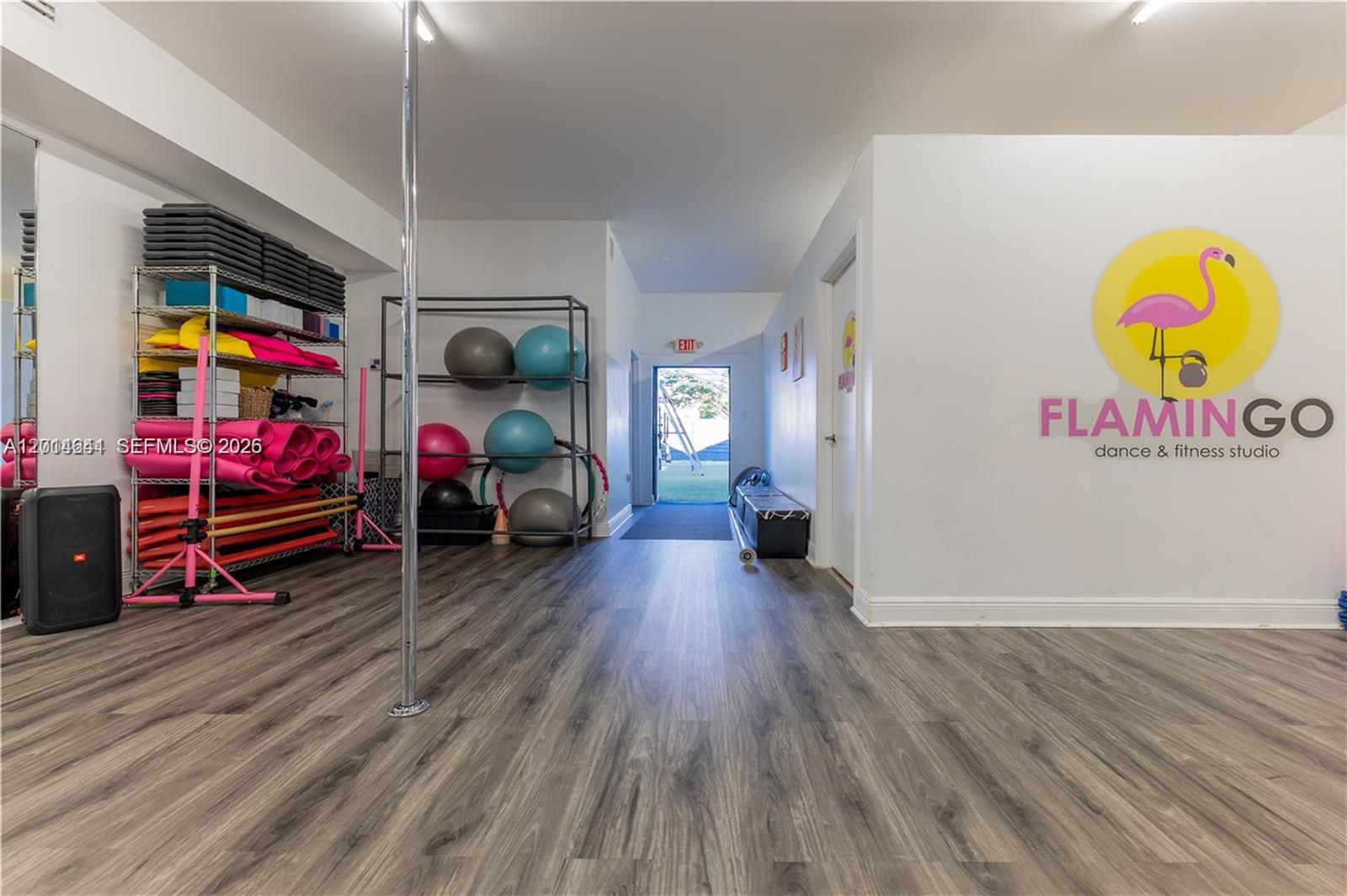 A fitness studio features wood-look flooring, a dance pole, storage racks, and a branded wall — 727 S 21st Ave, Hollywood FL 33020, HOLLYWOOD, FL
