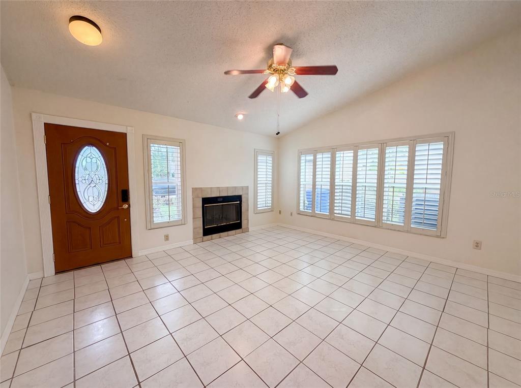 A living room features white tile floors, a fireplace, and a ceiling fan — 11648 HIDDEN HOLLOW CIRCLE, TAMPA, FL