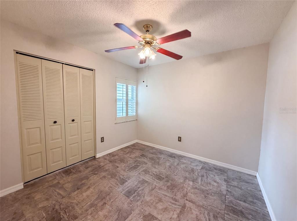 A bedroom with light walls, tile flooring, a ceiling fan, and bi-fold closet doors — 11648 HIDDEN HOLLOW CIRCLE, TAMPA, FL