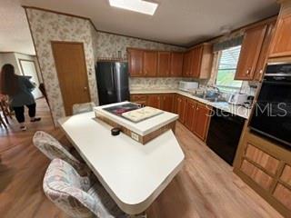 A kitchen features wood cabinets, a central island with a cooktop, and light-colored flooring — 2532 AMYRIS COURT UNIT 601, ZELLWOOD, FL