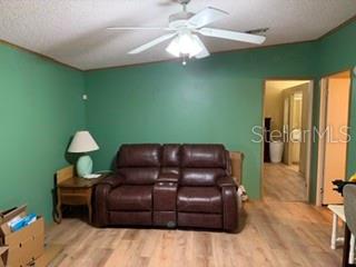 A living room features green walls, a brown leather loveseat, and light wood-look flooring — 2532 AMYRIS COURT UNIT 601, ZELLWOOD, FL