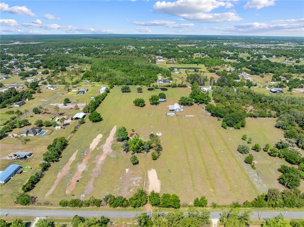 An aerial view shows a large, grassy rural property with several buildings and scattered trees — 3954 LA SALLE AVENUE, ST CLOUD, FL