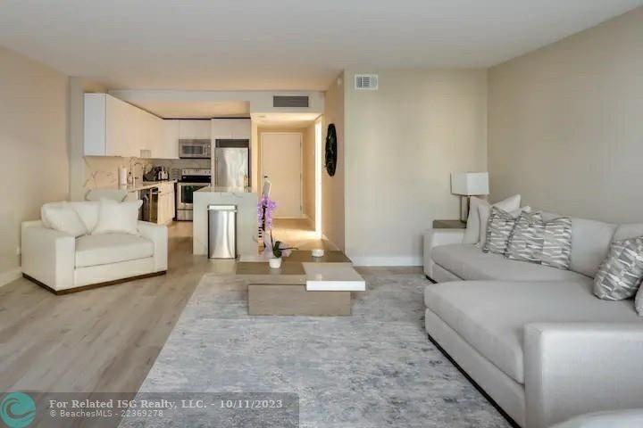 A living room with a white sofa and armchair opens to a modern kitchen area — 2301 Collins Avenue # 327, Miami Beach FL 33139, MIAMI BEACH, FL