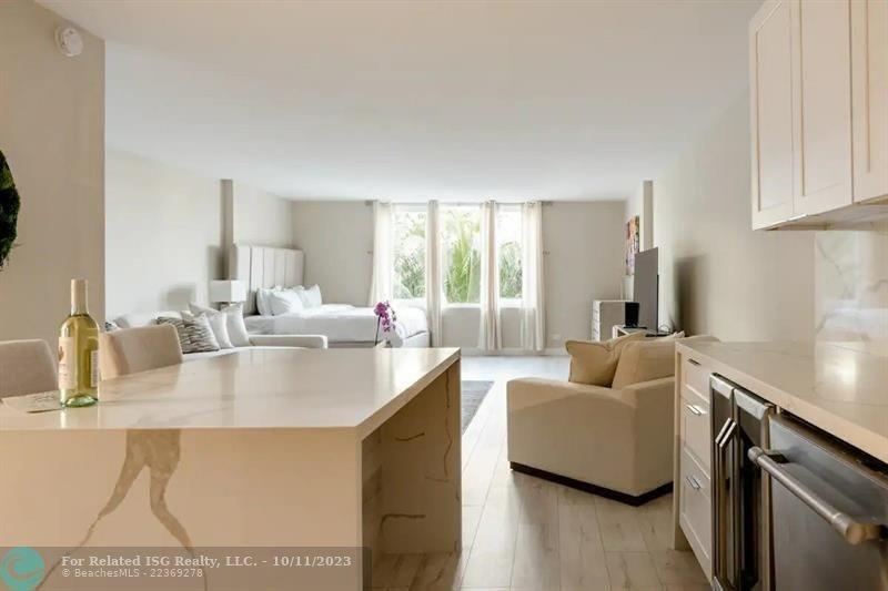 This studio apartment features an open kitchen with a stone island and a bedroom area — 2301 Collins Avenue # 327, Miami Beach FL 33139, MIAMI BEACH, FL
