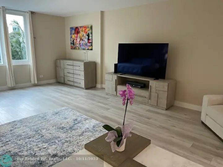 A living room features light wood flooring, a television on a console, and a dresser — 2301 Collins Avenue # 327, Miami Beach FL 33139, MIAMI BEACH, FL