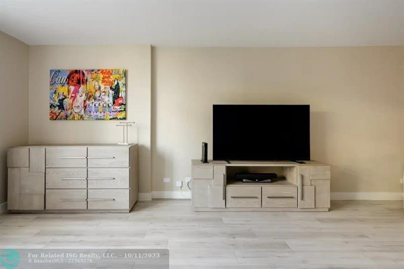 A living room features a television on a console, a dresser, and wall art — 2301 Collins Avenue # 327, Miami Beach FL 33139, MIAMI BEACH, FL
