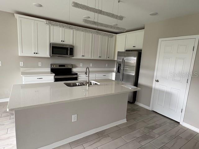 A kitchen features white cabinets, stainless steel appliances, a quartz island, and tile flooring — 5329 SENZA TRAIL, PALMETTO, FL