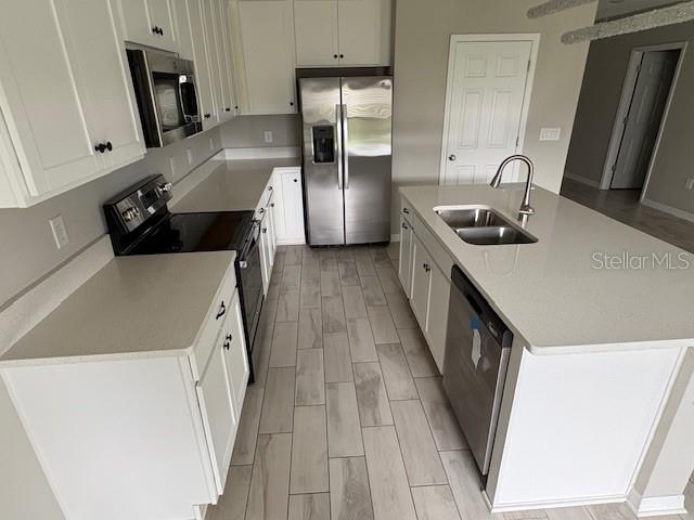 A modern kitchen features white cabinets, stainless steel appliances, and a central island with sink — 5329 SENZA TRAIL, PALMETTO, FL