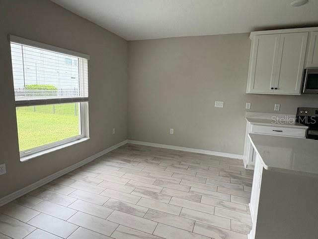 A dining area features light-colored tile flooring, a large window, and white kitchen cabinetry — 5329 SENZA TRAIL, PALMETTO, FL
