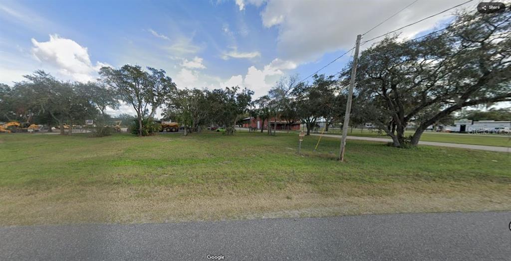 A grassy, vacant lot features several mature trees under a partly cloudy sky — N/A, POLK CITY, FL