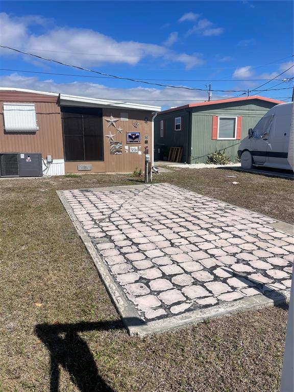 A paved patio area sits in front of a brown mobile home under a blue sky — 95 MICHIGAN STREET, PALMETTO, FL