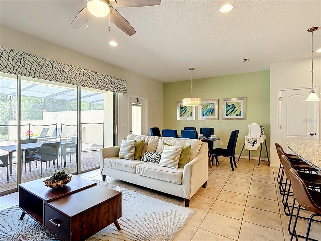 A living and dining area features tile floors, a beige sofa, and a green accent wall — 8899 GENEVE CT, KISSIMMEE, FL
