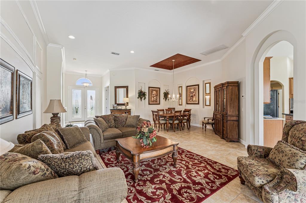 A living room and dining area with tile floors, a red rug, and arched doorways — 1949 DEERVIEW PLACE, LONGWOOD, FL