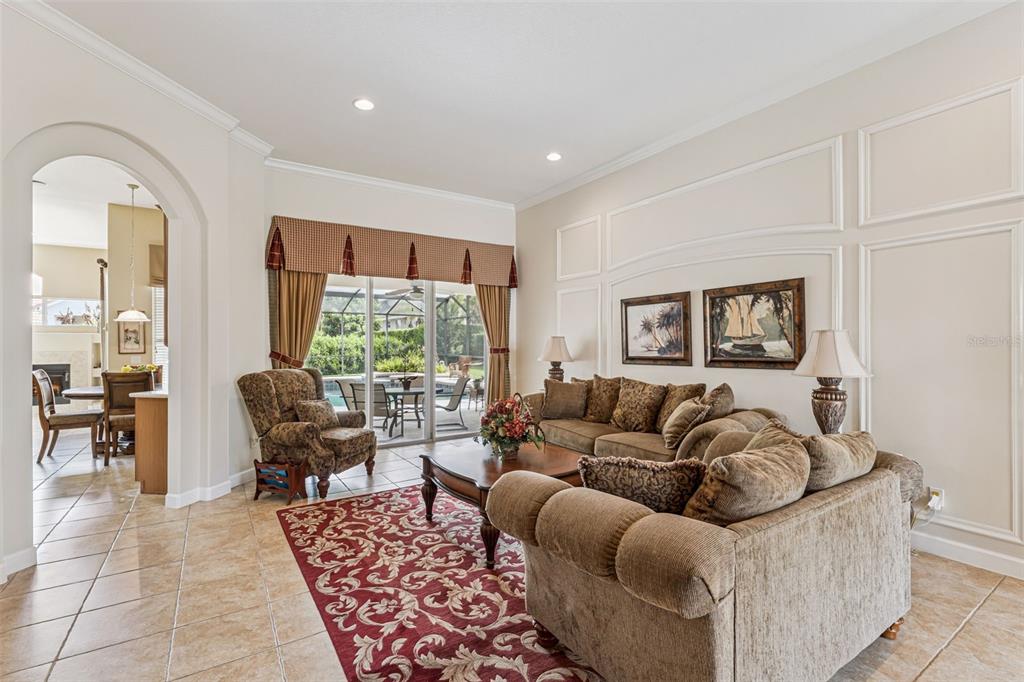 A living room with tile floors, a red patterned rug, and a view of a pool — 1949 DEERVIEW PLACE, LONGWOOD, FL
