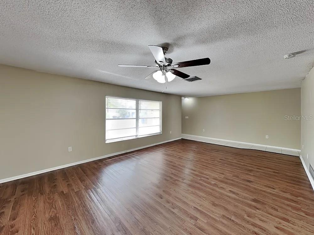 A spacious living room features light-colored walls, wood-look flooring, and a ceiling fan — 8900 PHYLISS AVENUE, SARASOTA, FL