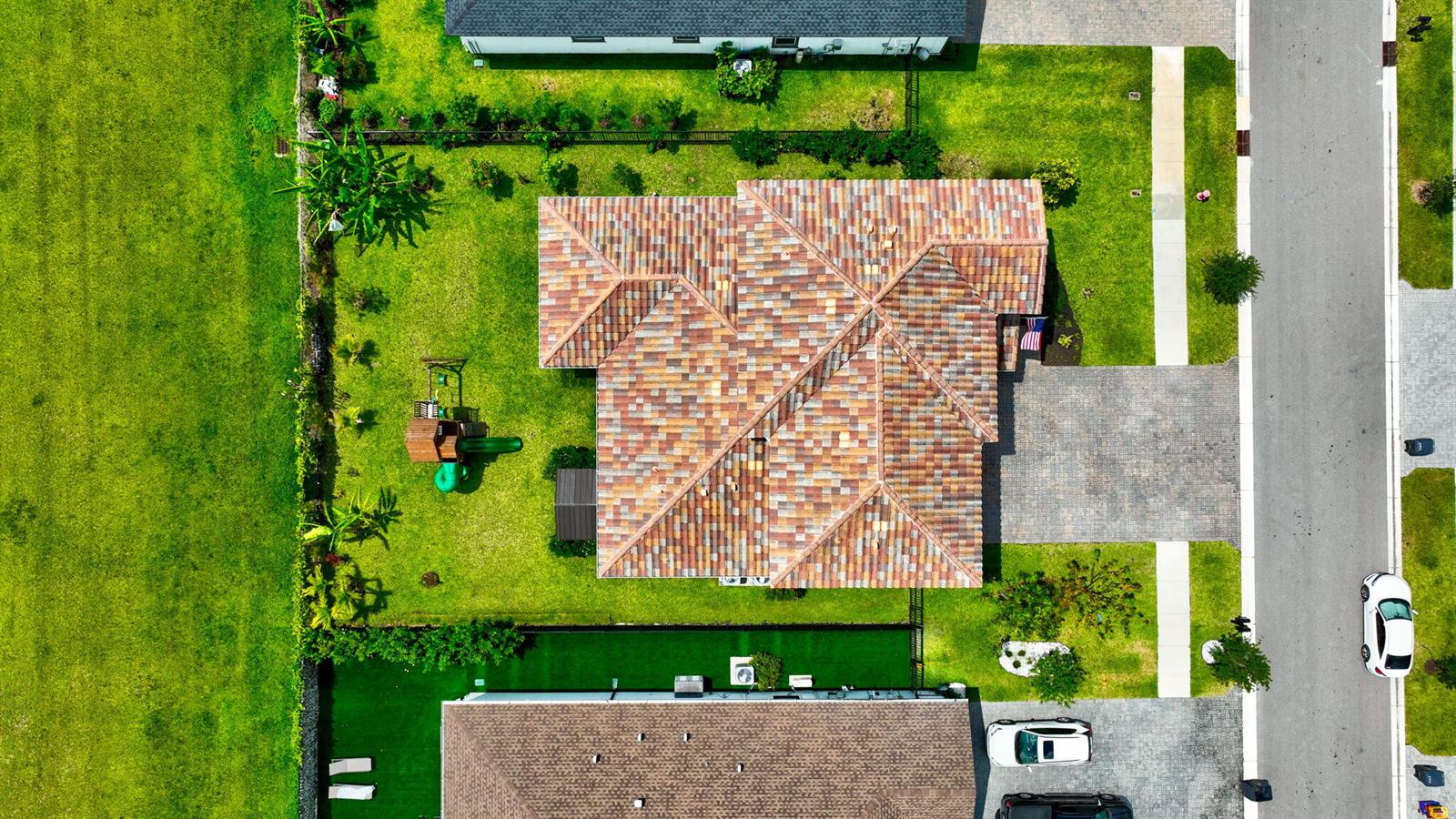 An aerial view of a house with a multi-faceted tile roof and a backyard playground — 1136 Tangled Orchard Trace, Loxahatchee FL 33470, LOXAHATCHEE, FL