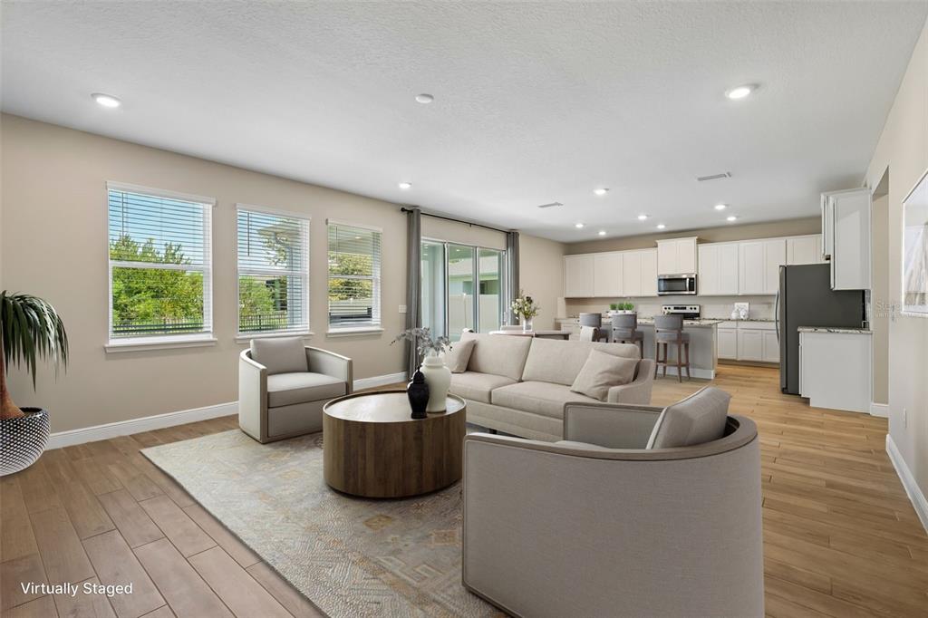 A living room with light wood floors, neutral furniture, and an open-concept kitchen — 1297 BERING ROAD, WESLEY CHAPEL, FL