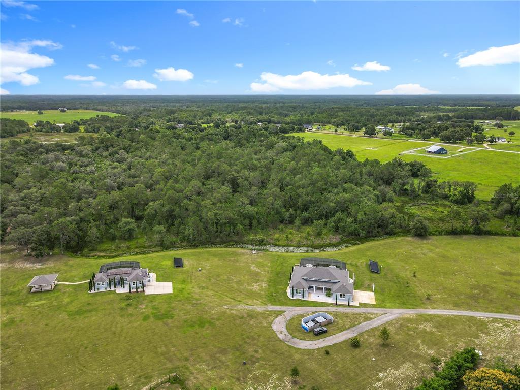 An aerial view shows two houses with solar panels on a large, grassy rural lot — 10220 & 10224 BAY LAKE ROAD, GROVELAND, FL