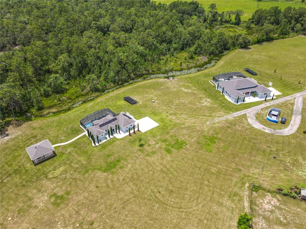 An aerial view shows two houses with screened pools and a detached structure on acreage — 10220 & 10224 BAY LAKE ROAD, GROVELAND, FL