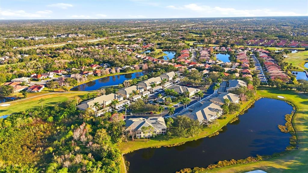 An aerial view shows a residential complex with multiple buildings situated near several ponds — 6342 GRAND OAK CIRCLE UNIT 204, BRADENTON, FL