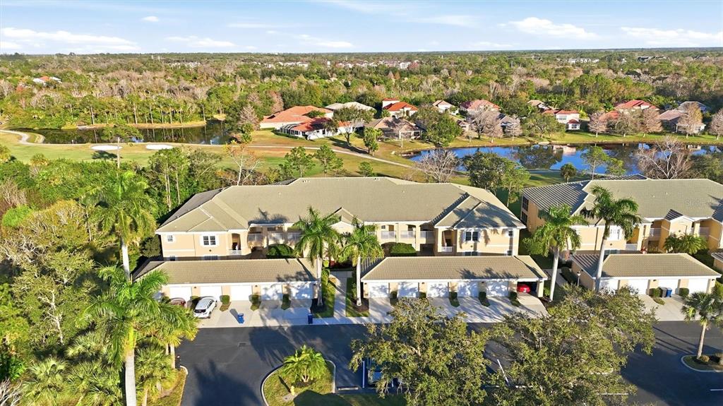 An aerial view shows a multi-unit residential building with attached garages and surrounding landscaping — 6342 GRAND OAK CIRCLE UNIT 204, BRADENTON, FL