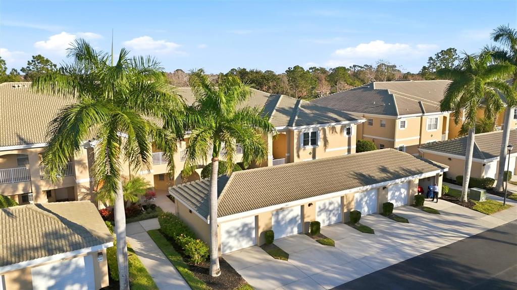 An aerial view of multi-story residential buildings with attached garages and palm trees — 6342 GRAND OAK CIRCLE UNIT 204, BRADENTON, FL