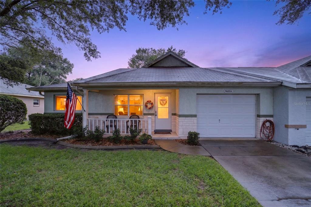 A single-story house with a white garage, a front porch, and an American flag — 9632 SW 95TH COURT UNIT A, OCALA, FL