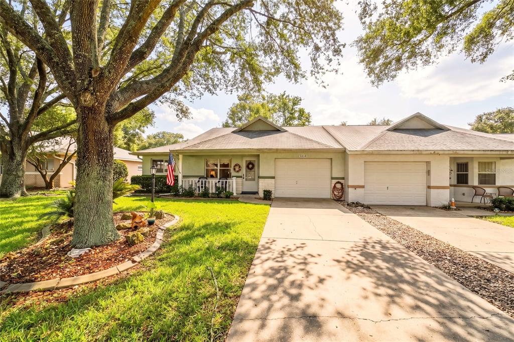 A single-story duplex with two garages, a front porch, and a large tree in the yard — 9632 SW 95TH COURT UNIT A, OCALA, FL