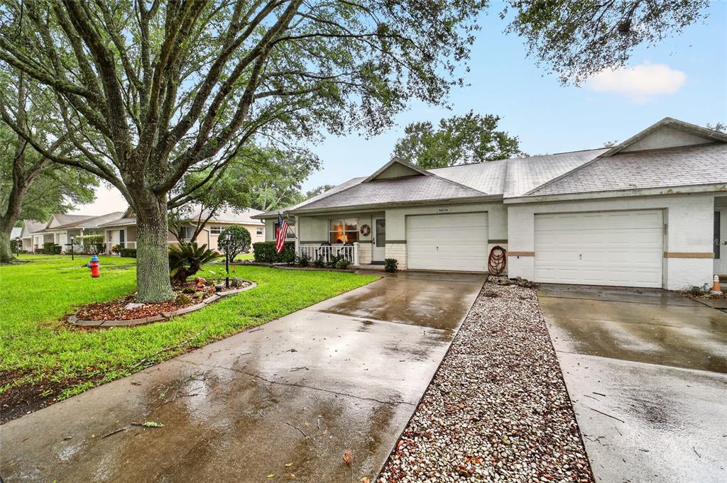A single-story duplex with two garage doors, a concrete driveway, and a large front tree — 9632 SW 95TH COURT UNIT A, OCALA, FL