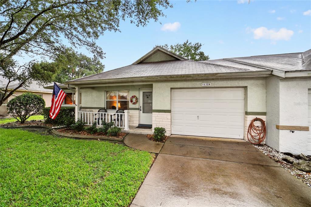 A single-story house features a white garage, a front porch, and an American flag — 9632 SW 95TH COURT UNIT A, OCALA, FL