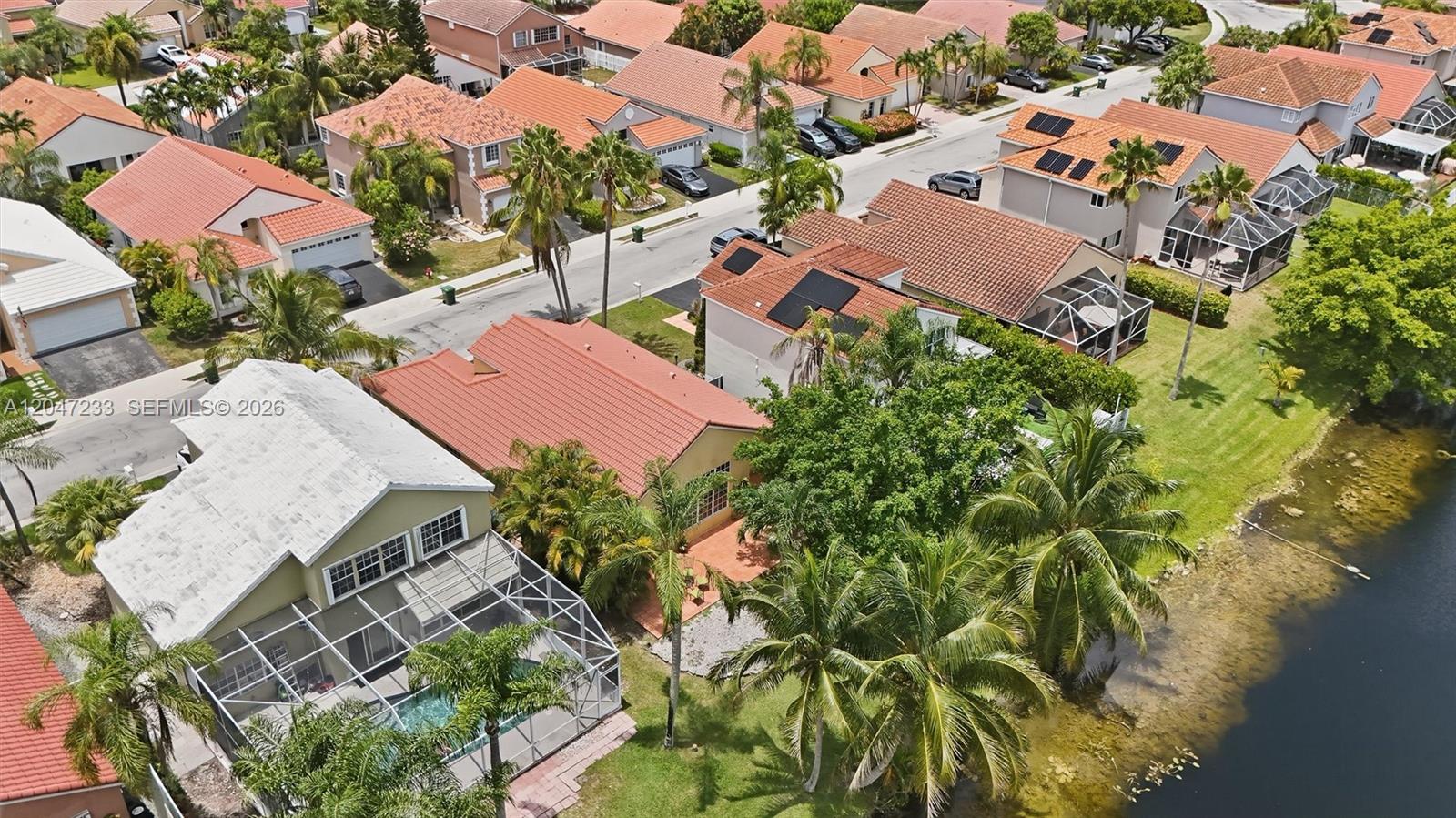 An aerial view shows a suburban neighborhood with houses, swimming pools, and palm trees — 411 Bermuda Springs Dr, Weston FL 33326, WESTON, FL