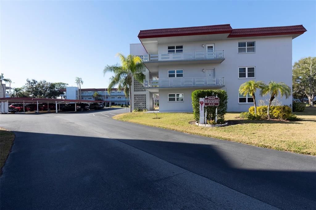 A three-story apartment building with covered parking and a sign in the front yard — 5660 80TH STREET N UNIT A202, ST PETERSBURG, FL