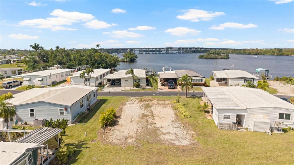 An aerial view shows a vacant residential lot situated between two manufactured homes near water — 362 SHORELAND DRIVE, FORT MYERS, FL