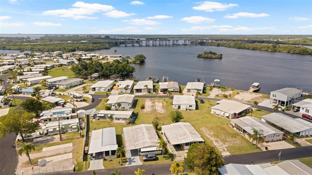 An aerial view shows a mobile home community situated along a river with a bridge — 362 SHORELAND DRIVE, FORT MYERS, FL