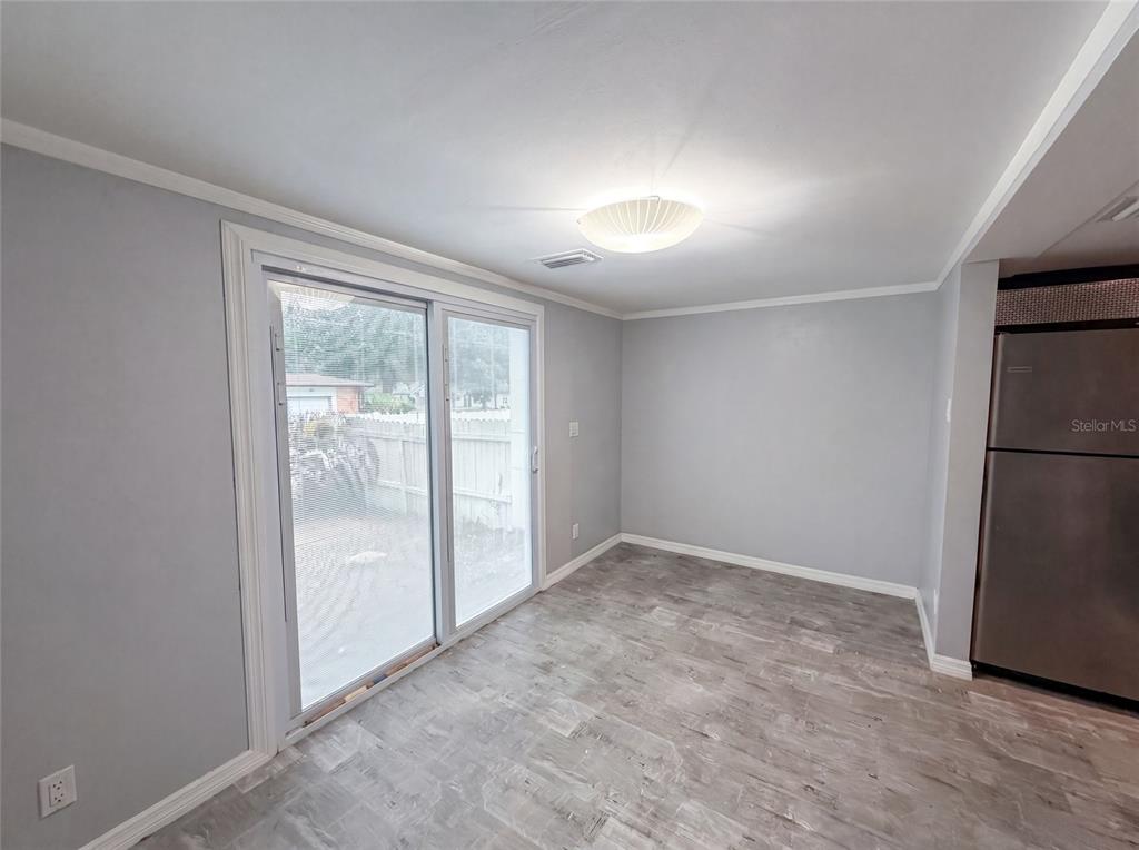 A dining area features gray walls, wood-look flooring, a ceiling light, and sliding glass doors — 2308 S PARK AVENUE, SANFORD, FL